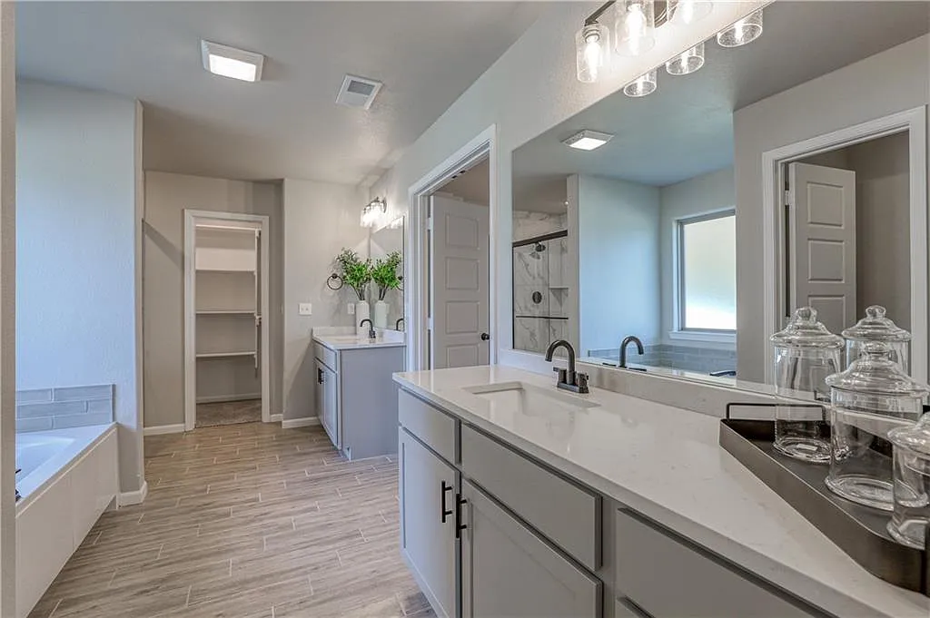 Bathroom with double vanity, walk-in shower, and walk-in closet